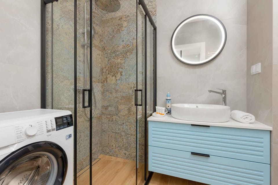 A bathroom with a washing machine and shower.
