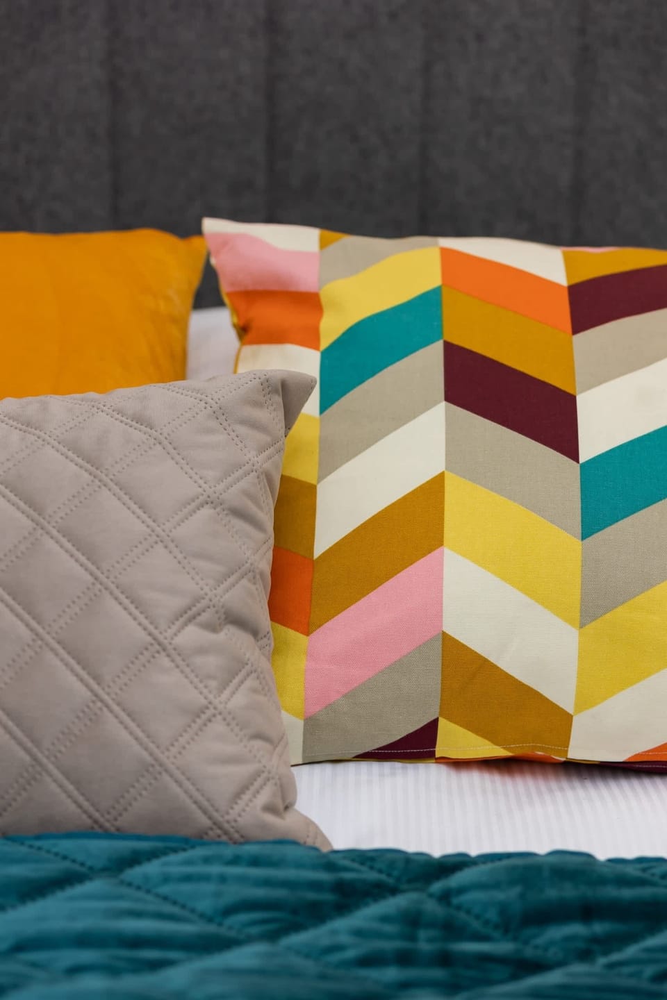 A close-up of colorful and patterned cushions on a bed, adding a playful touch.
