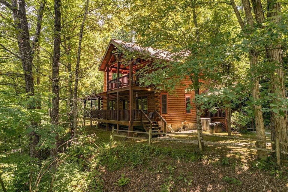 Covered wraparound deck overlooking a wooded landscape with outdoor seating and rustic log cabin details in the Smoky Mountains area.