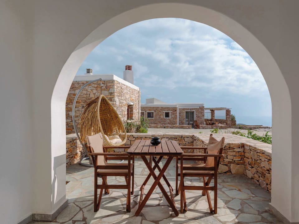 Shaded dining terrace with an arched opening overlooking the stone courtyard.