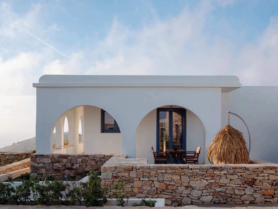 Front view of the home featuring classic Cycladic curves and natural stonework.