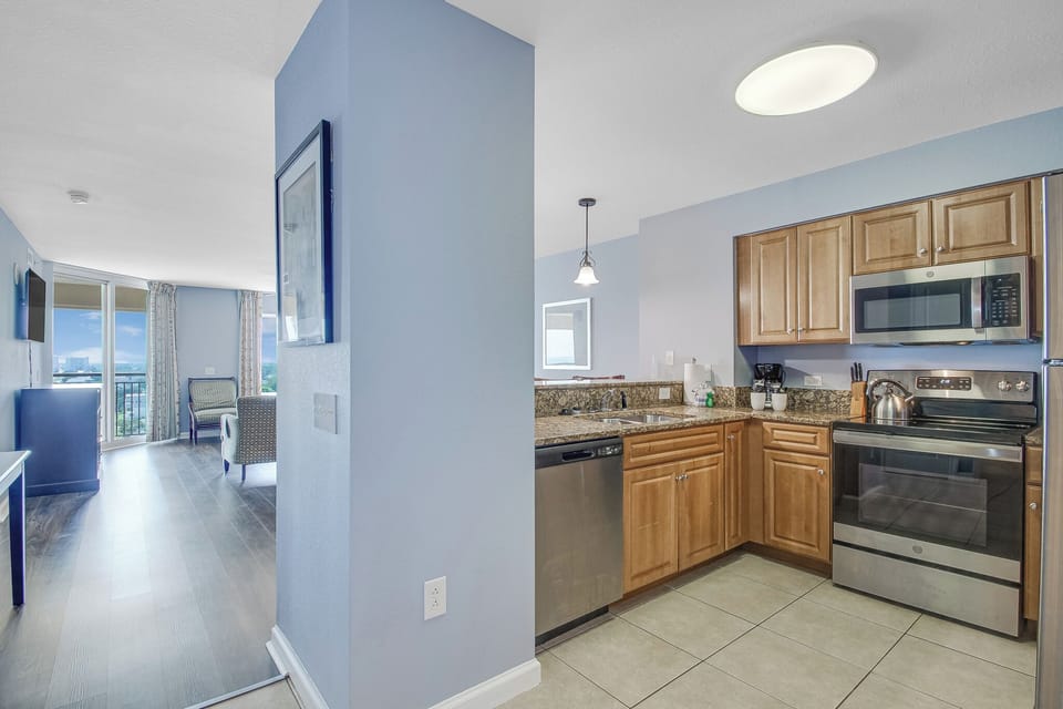 Your fully equipped kitchen features granite counters and stainless steel appliances, flowing seamlessly into your bright living space.