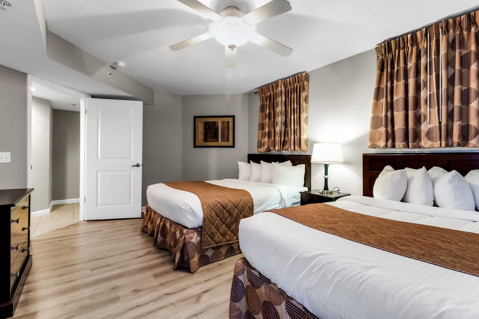 Relax in your spacious room with two comfortable queen beds, crisp linens, and warm brown accents that create a cozy atmosphere.