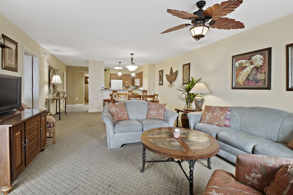 Settle into your spacious living room with tropical ceiling fan, plush seating, and open layout connecting to the dining area.