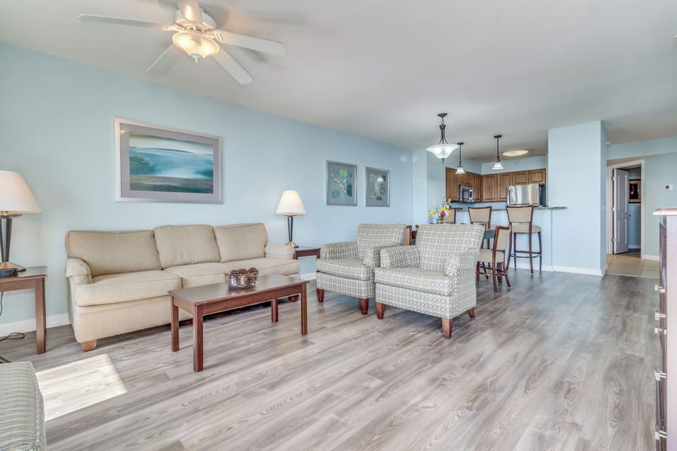 Relax in your spacious open-concept living area with comfortable seating, modern kitchen, and soothing coastal decor that creates the perfect home away from home.