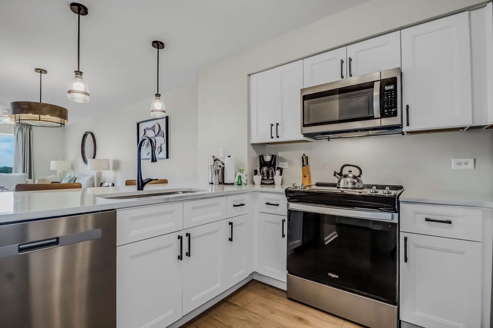 Your modern kitchen features sleek white cabinets, stainless steel appliances, and stylish pendant lighting for memorable meal preparation.