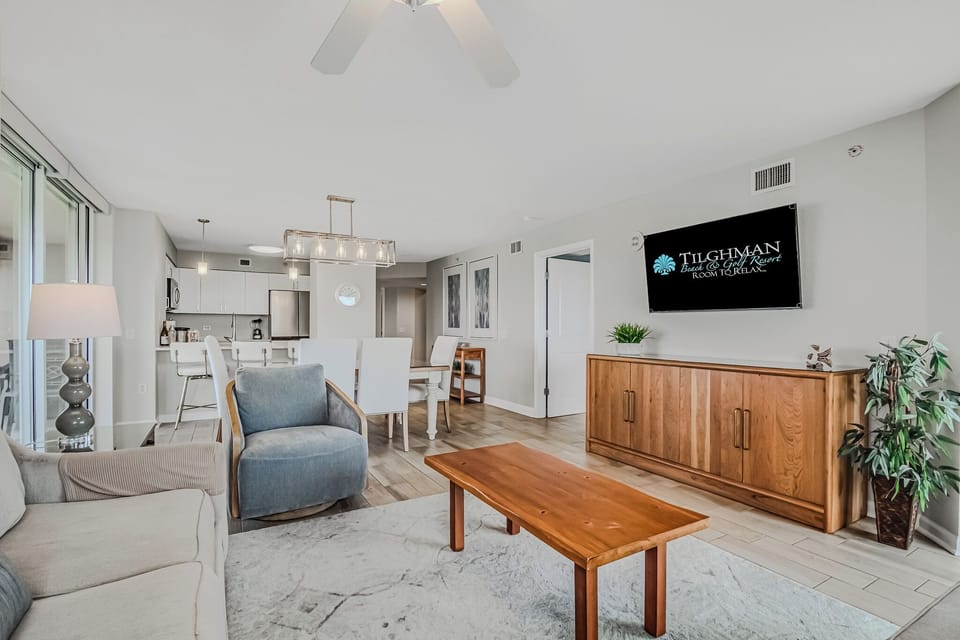Relax in your spacious open-plan living area with modern furnishings, ceiling fan, and warm wood accents creating the perfect home base.