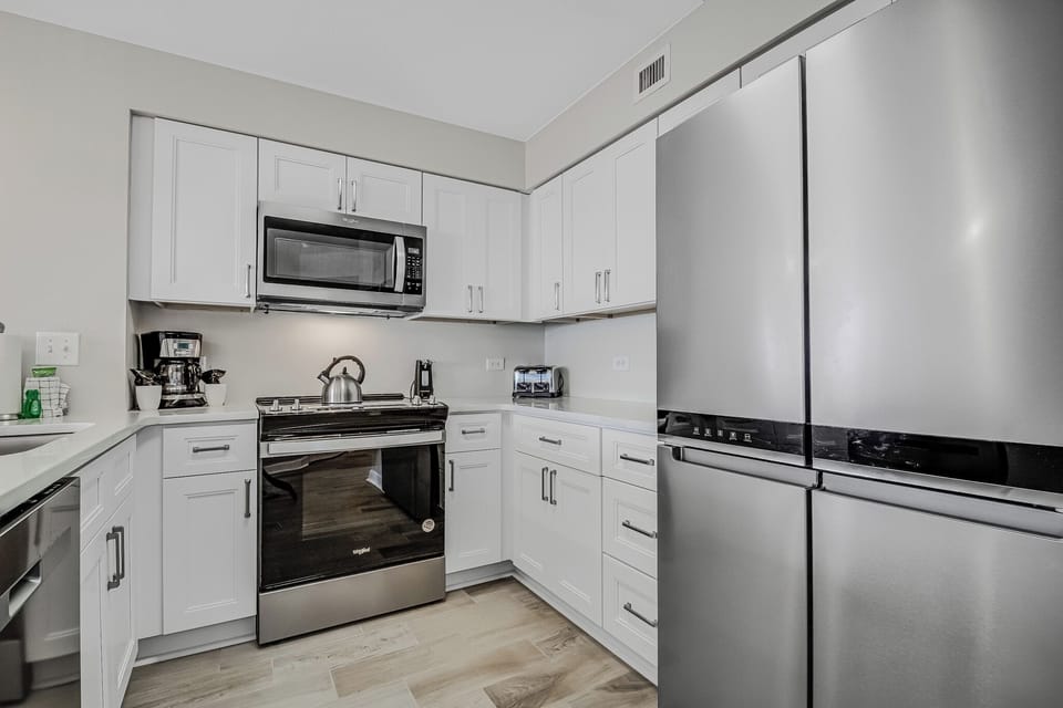 Your fully equipped kitchen features sleek white cabinets, stainless steel appliances, and everything you need to prepare delicious meals during your stay.