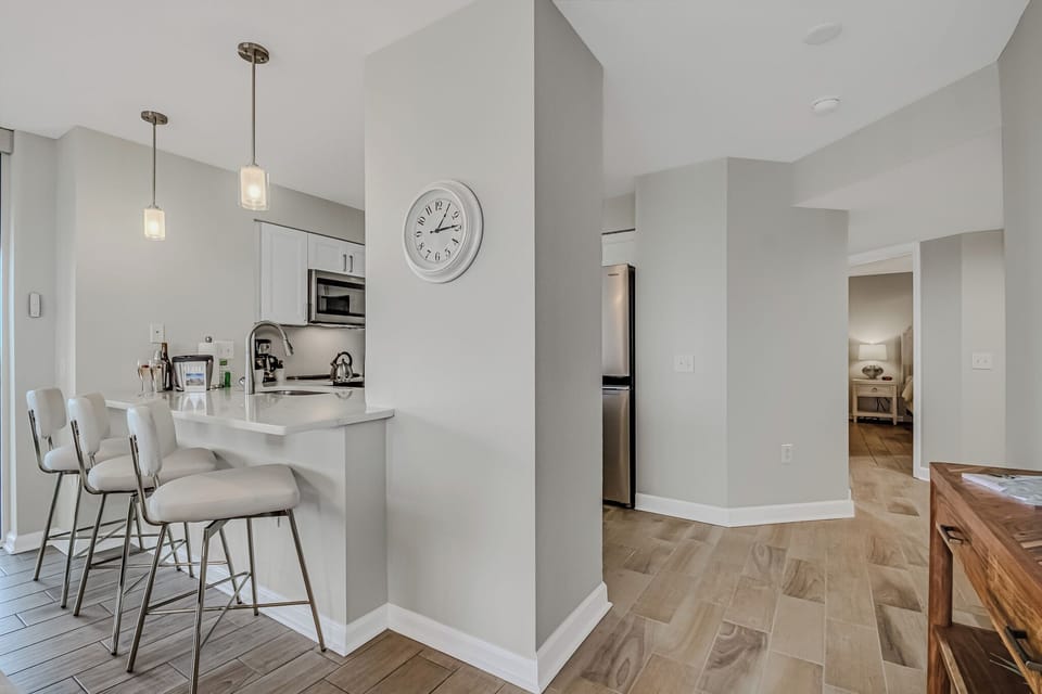 Your modern kitchen features sleek white cabinetry, a breakfast bar with stylish stools, and contemporary pendant lighting.