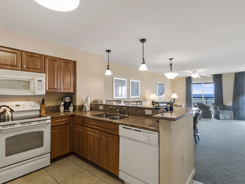 Your fully equipped kitchen flows seamlessly into the living space, with granite counters and ocean views creating the perfect backdrop for your beach getaway.