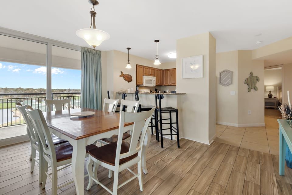 Gather for meals at your spacious dining table with golf course views streaming through floor-to-ceiling windows, creating the perfect backdrop.