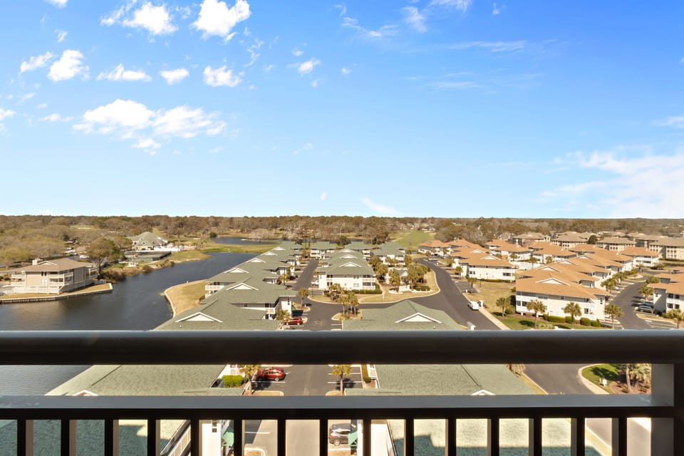 Elevated view showcases a peaceful waterfront community with modern homes, winding waterways, and residential neighborhoods under expansive blue skies.