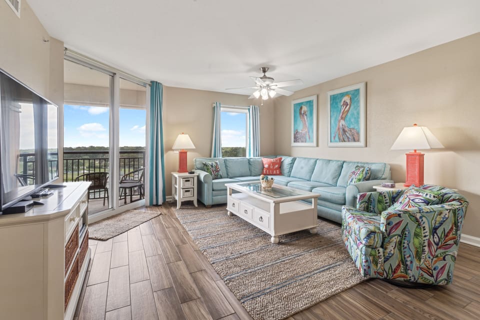 Sink into this bright living room where coral accents and coastal art create your perfect relaxation space with balcony views.