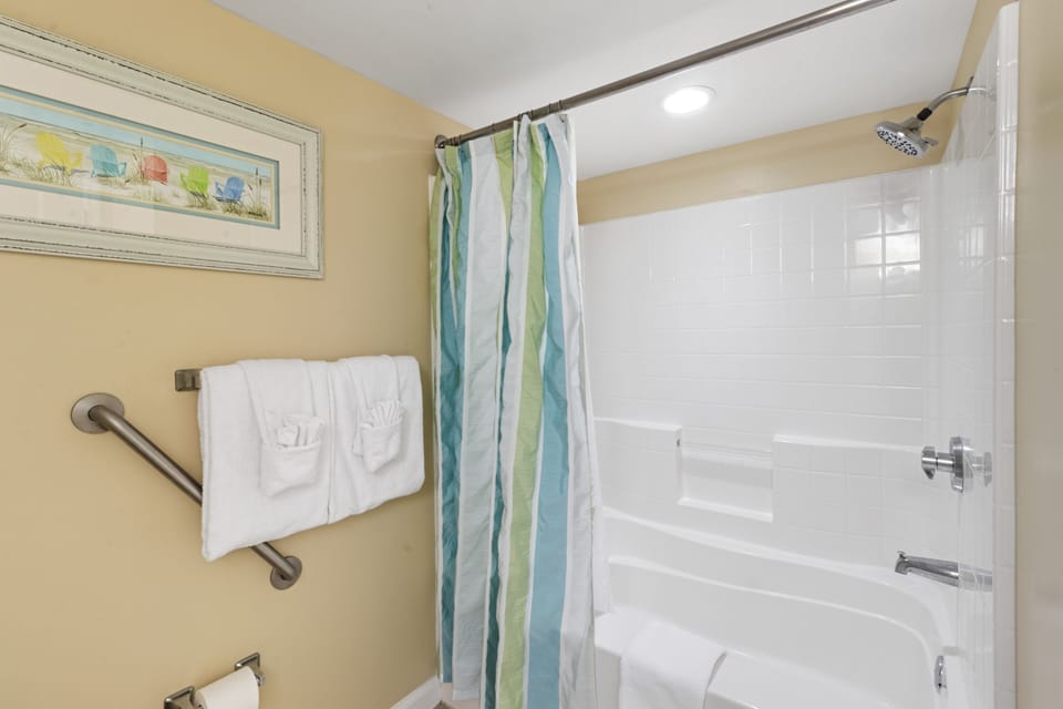 Step into your private bathroom sanctuary with a spacious tub-shower combo, fresh towels, and coastal-inspired décor for a refreshing start to your day.