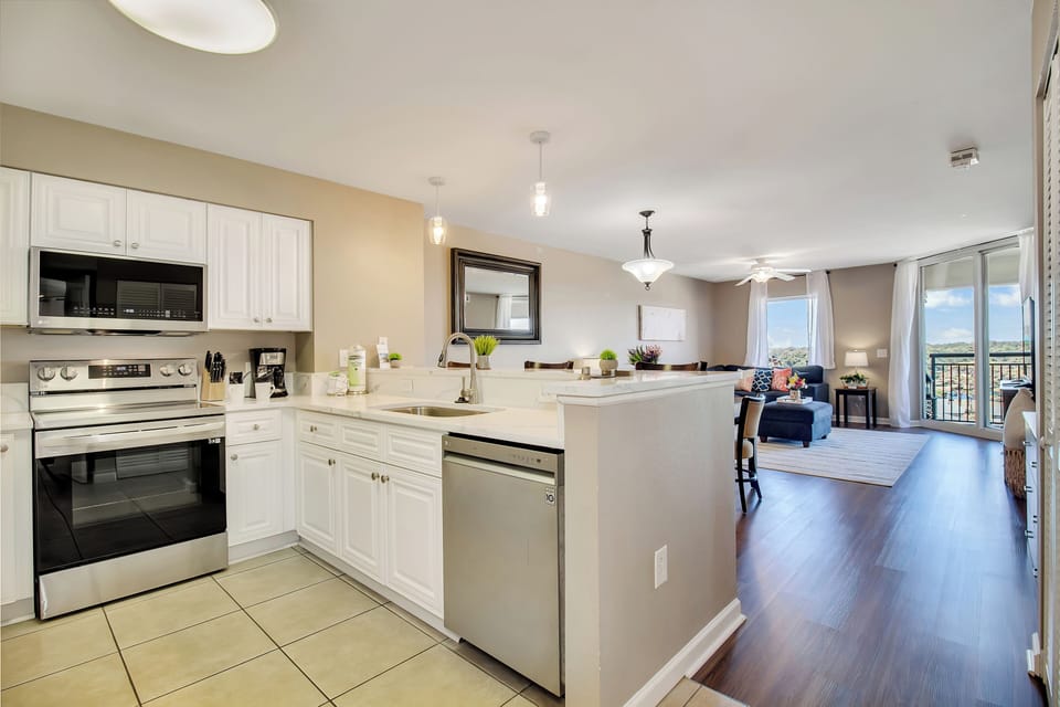 Your spacious open-plan kitchen flows seamlessly into the living area, where you can prepare meals while enjoying conversation and city views through expansive windows.