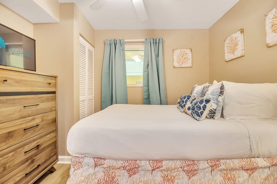 Your cozy bedroom retreat features coastal charm with soft linens, nautical accents, and gentle natural light filtering through seafoam curtains.