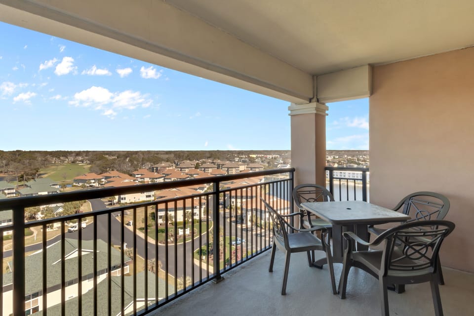 Your private balcony offers sweeping views of the neighborhood below, perfect for morning coffee or evening relaxation at your outdoor dining table.