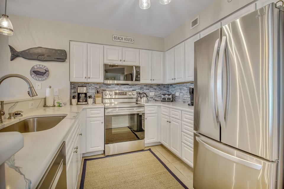Your fully equipped kitchen invites you to prepare meals with coastal charm and modern stainless steel appliances.