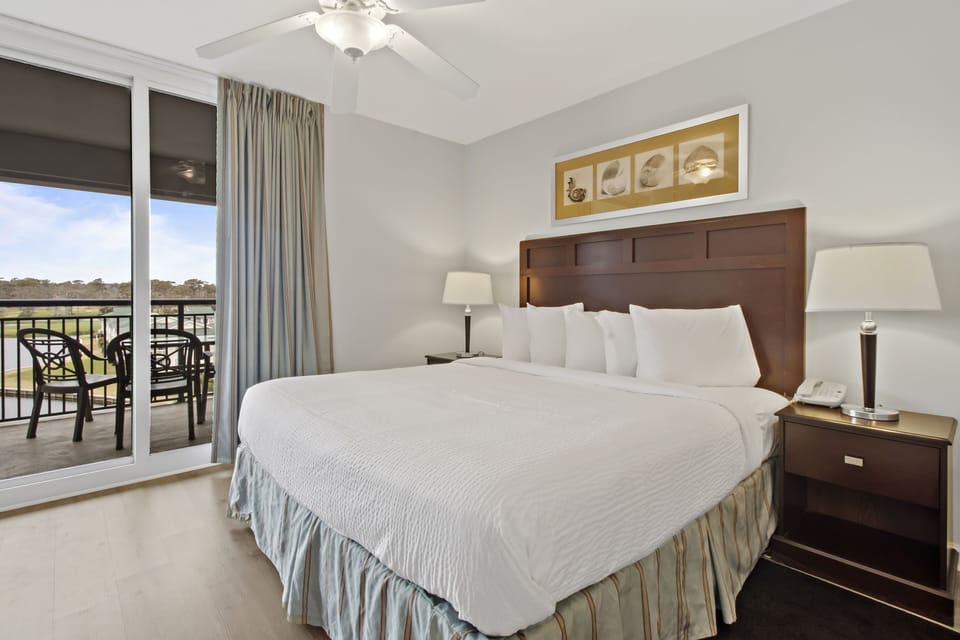 Sink into crisp white linens in your bright bedroom with elegant furnishings and private balcony access.