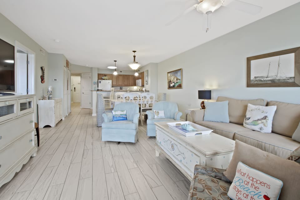 Relax in this bright, coastal-themed living space where soft blues meet comfortable seating and an open kitchen awaits your culinary adventures.