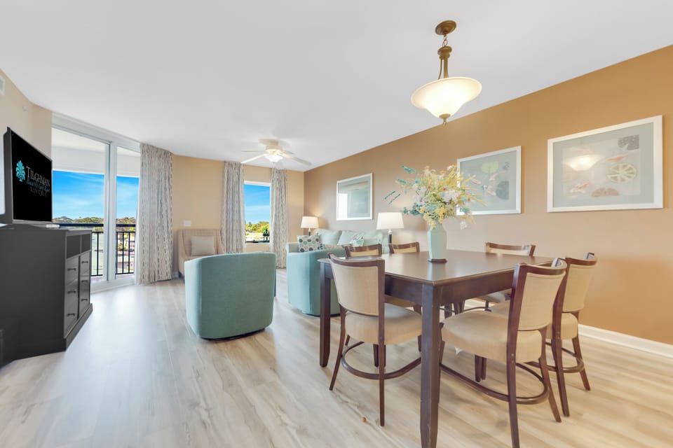 Your elegant dining space flows seamlessly into the living area, with warm natural light streaming through expansive windows showcasing beautiful outdoor views.