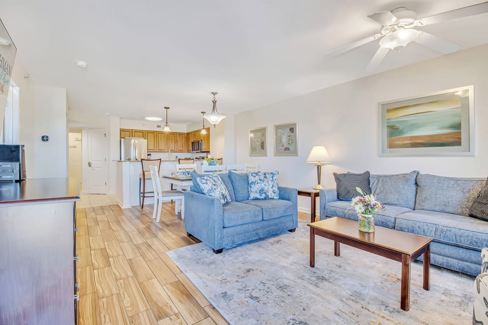 Relax in your spacious open-plan living area with coastal blue sofas and hardwood floors connecting to a fully equipped kitchen.