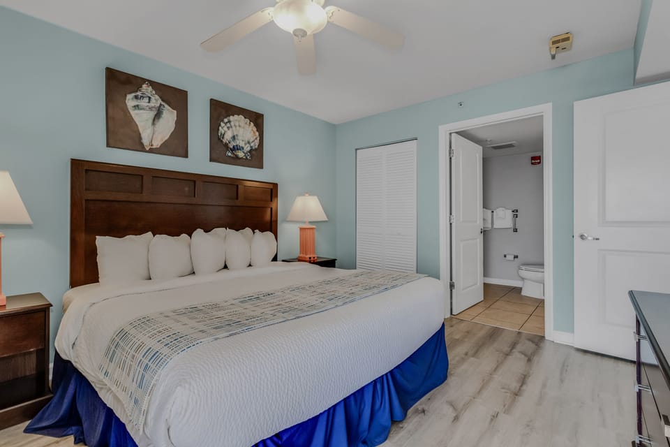 Drift off to sleep in your comfortable coastal bedroom, where soft blue walls and seashell artwork create a peaceful seaside retreat.