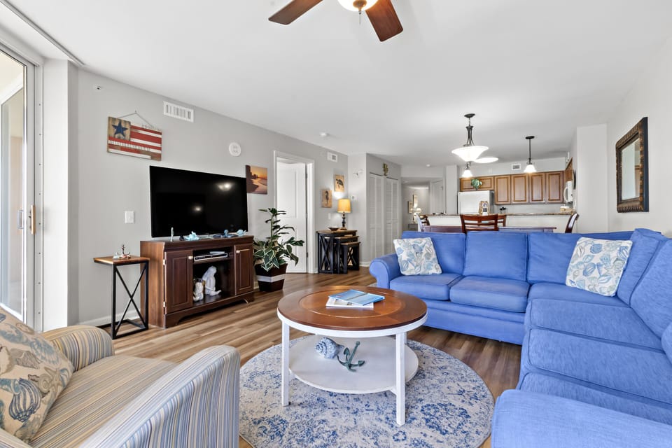 Sink into your bright, coastal-themed living room with comfy blue seating and open kitchen for memorable evenings together.