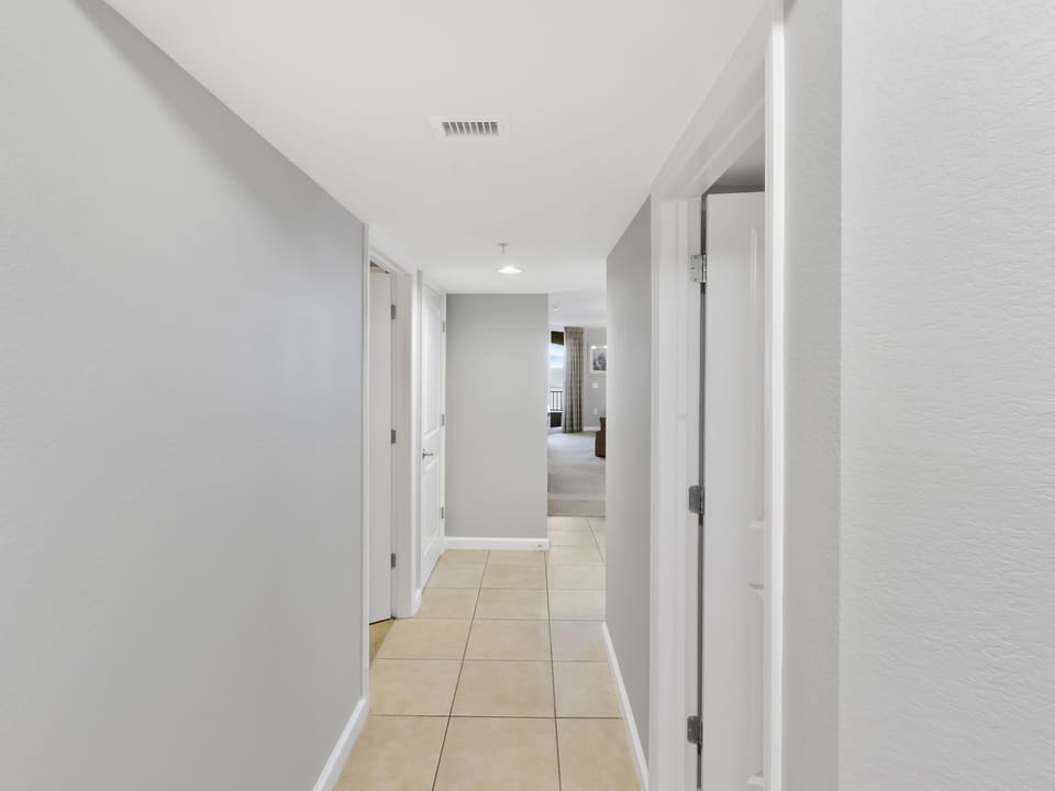 Bright, spacious hallway with clean tile floors leads you to comfortable living spaces beyond.