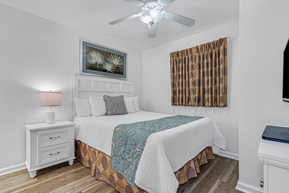 Your cozy bedroom features crisp linens, tropical artwork, and a gentle ceiling fan for perfect comfort.