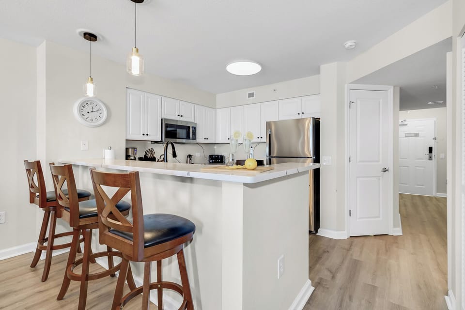 Your modern kitchen welcomes you with crisp white cabinets, stainless steel appliances, and a breakfast bar perfect for morning coffee.