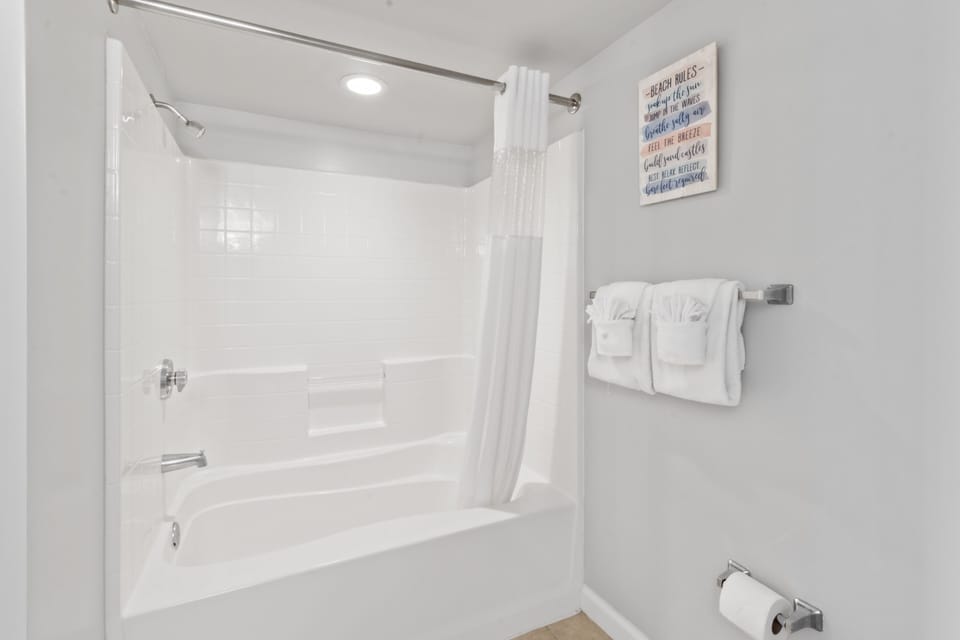 Unwind in your pristine bathroom featuring a deep soaking tub with modern shower combination and fresh towels awaiting your arrival.