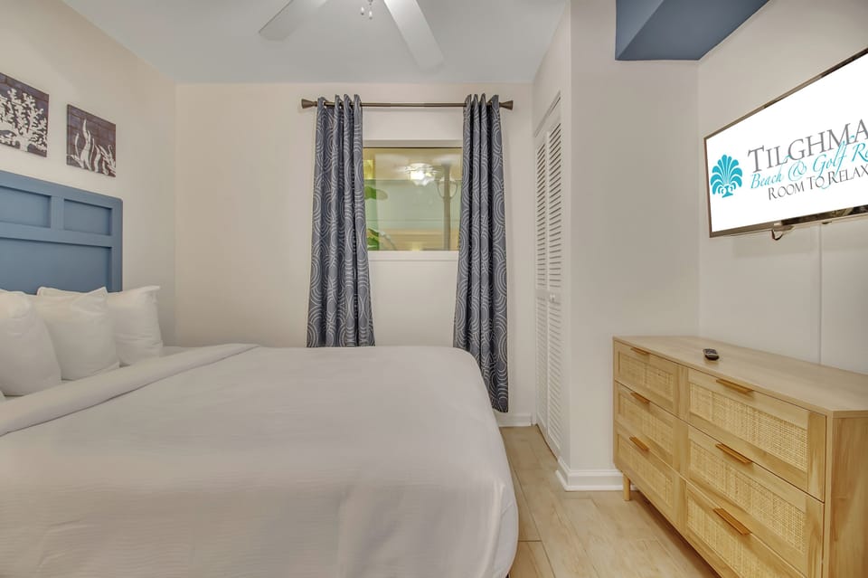 Sink into crisp white linens on your comfortable bed, while natural light filters through elegant curtains in this thoughtfully designed bedroom.