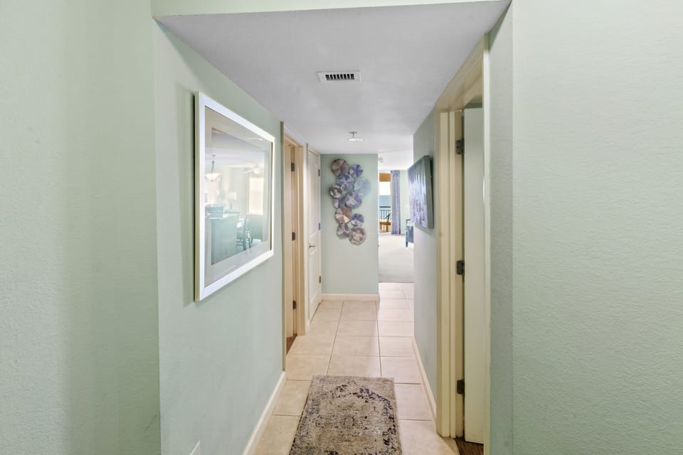 Step into your bright, welcoming hallway with beautiful ocean-themed artwork guiding you toward panoramic balcony views.