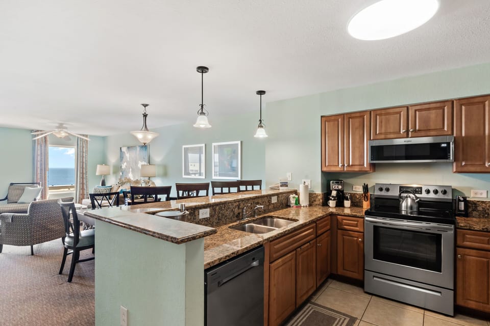 Your fully equipped kitchen with granite counters and breakfast bar opens to the dining area, perfect for preparing meals and gathering.