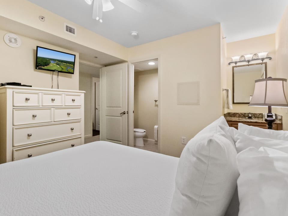 Sink into crisp white linens in your peaceful bedroom, complete with TV for entertainment and easy bathroom access nearby.