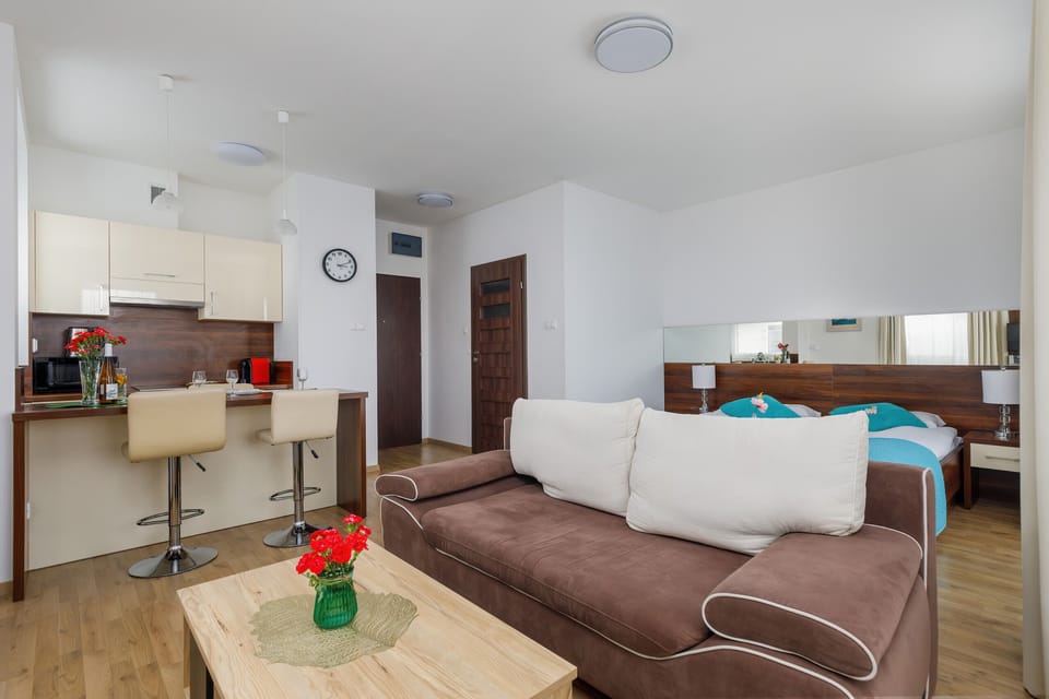 A living room featuring a wall-mounted TV, a brown couch, and a small wooden coffee table.