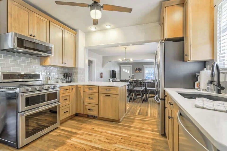 Cook and prep with plenty of wood cabinetry, a stainless range, and tiled backsplash—then plate up at the long counter before heading to the dining area beyond.