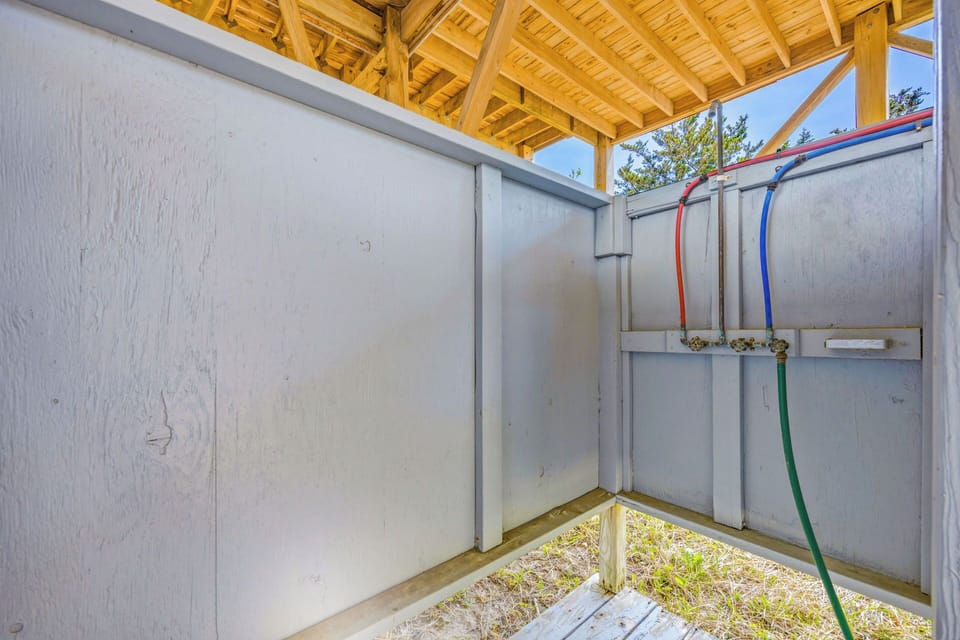 Semi-private outdoor shower with rustic wooden roof overhang, perfect for rinsing off after beach days or pool time.