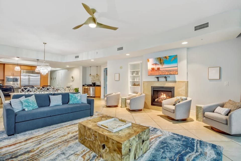 Step into a stunning open-concept living space featuring cozy coastal decor, a warm fireplace, and a seamless flow into a gourmet kitchen. With plush seating, ocean-inspired accents, and a serene ambiance, this is the ultimate place to unwind. 
