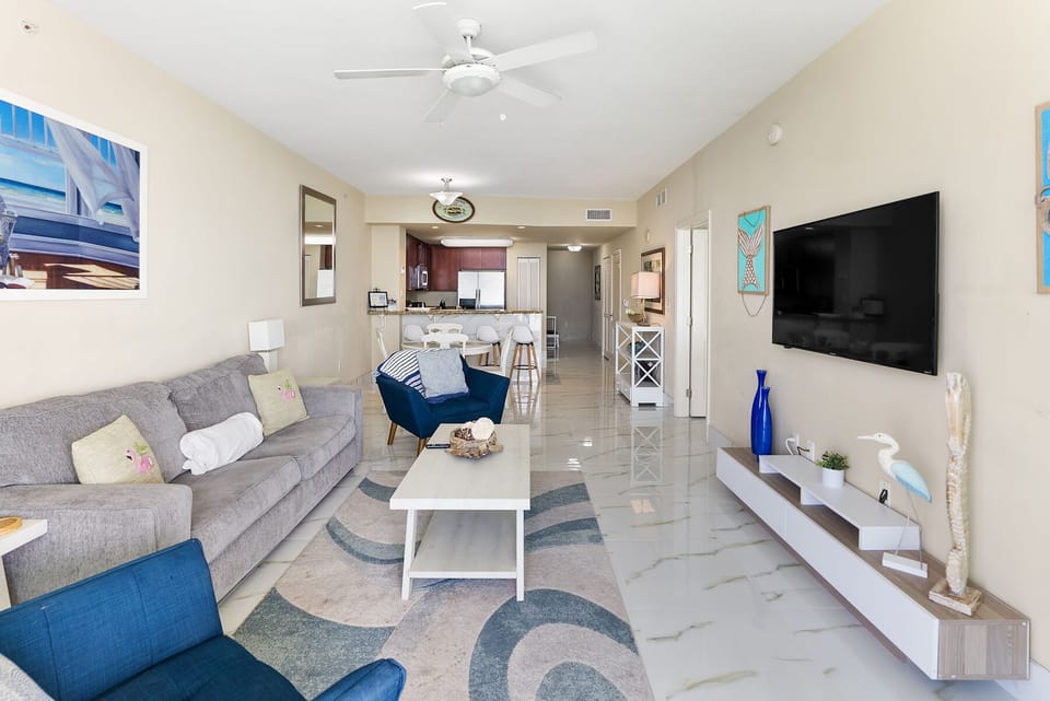 Unwind in your bright, modern living space with plush seating, entertainment center, and open-concept design flowing to the kitchen.