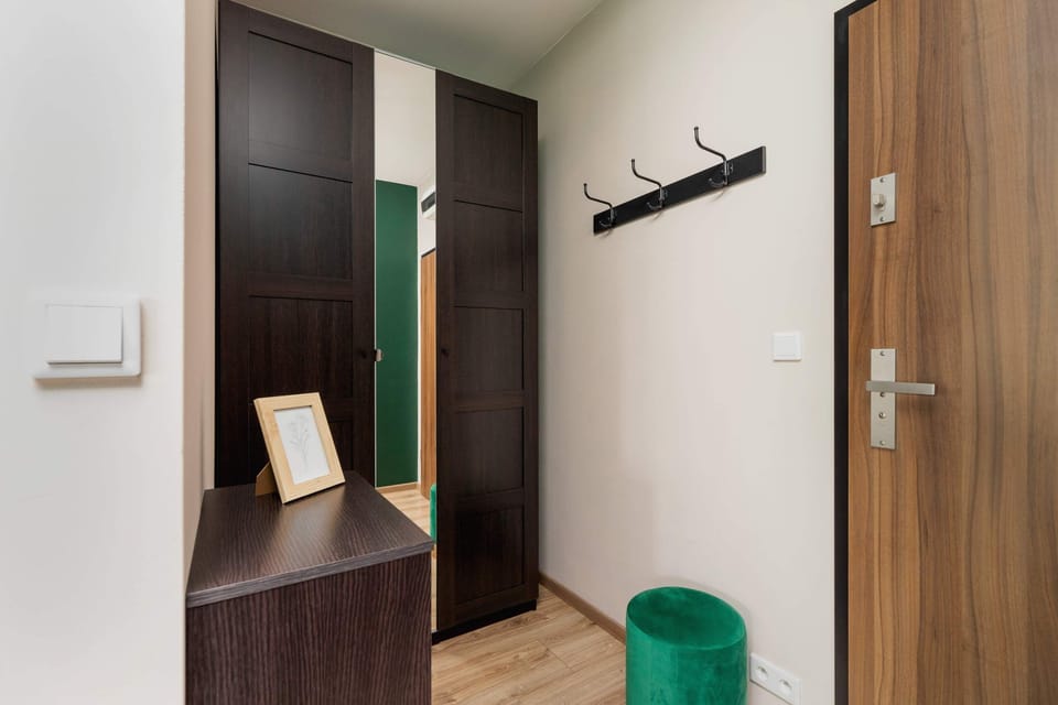A wooden door leads to a modern hallway with clean, minimal decor. The design emphasizes functionality and simplicity.