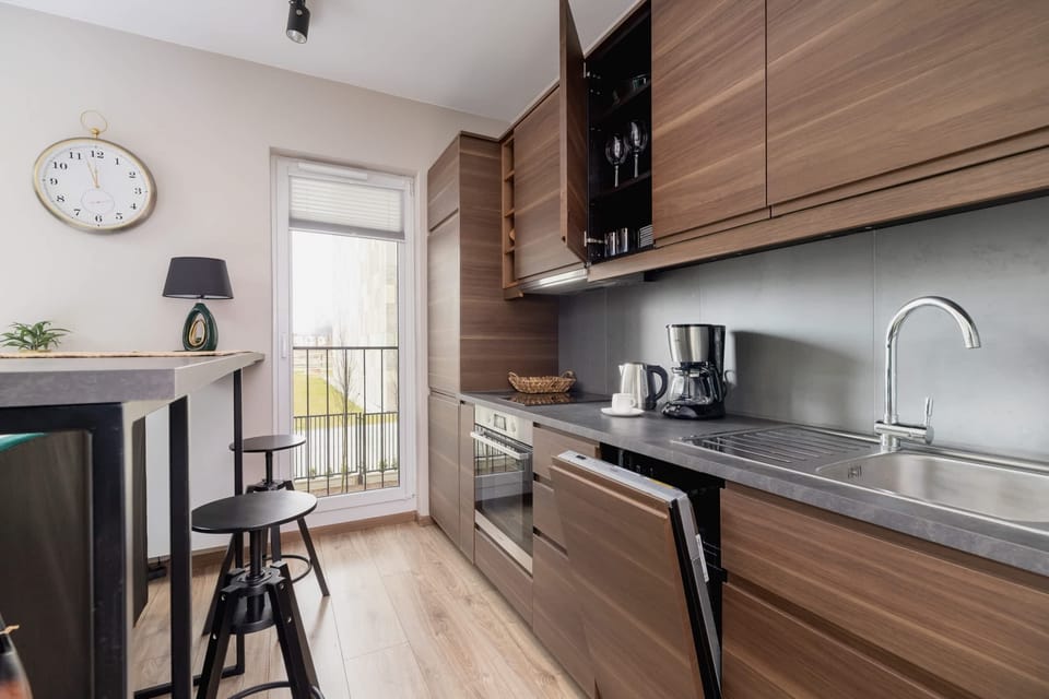 A combined kitchen and dining space with dark wood furniture and green accents. A small table and stools complete the cozy dining area.