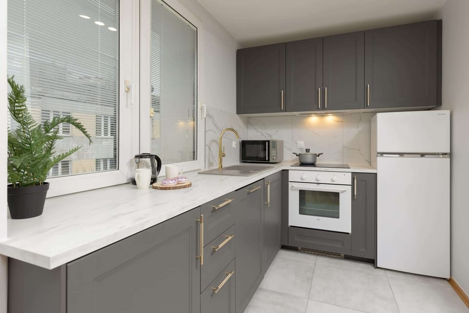 A modern kitchen equipped with gray cabinets, a microwave, and clean white countertops.
