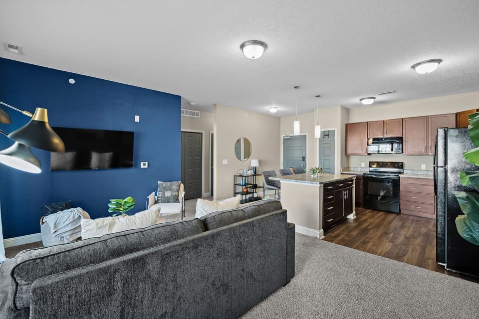 Open-concept living and kitchen area featuring a bold accent wall, upgraded pendant lighting, and modern finishes—designed to feel bright, stylish, and comfortable for everyday living or longer stays.