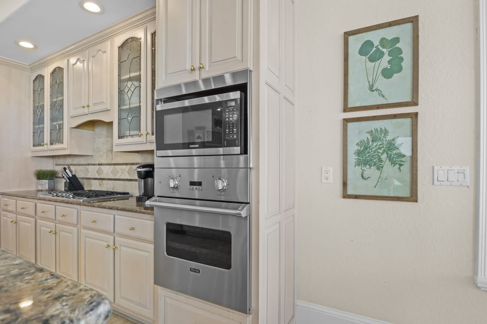 Your gourmet kitchen features elegant white cabinetry, granite counters, and premium stainless steel appliances for effortless meal preparation.