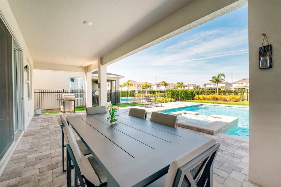 Enjoy alfresco dining by the pool in this elegant patio setting, perfect for family gatherings and relaxation.