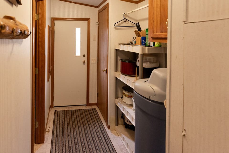 Hallway leading to primary bathroom and side door exit by the garage.