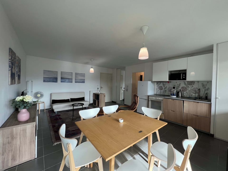 Coin repas avec table pour 5 personnes et cuisine en arrière-plan