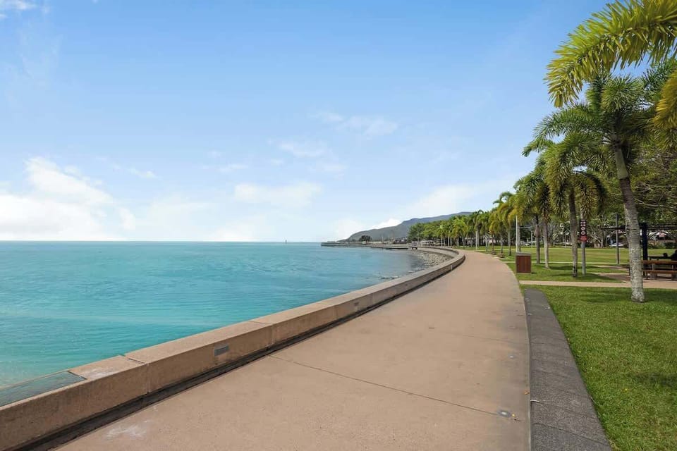 Discover the beauty of Cairns' iconic waterfront promenade, lined with palm trees, walking paths and scenic water views.